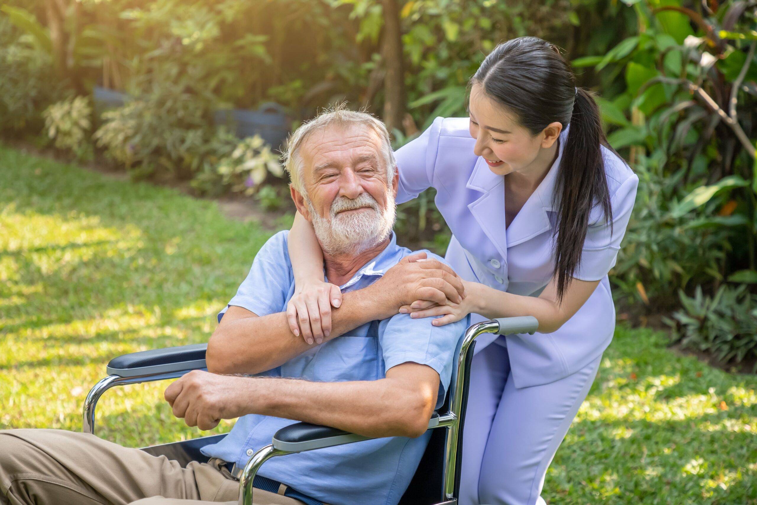 happy-nurse-holding-elderly-man-hand-wheelchair-garden-nursing-home